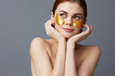 young woman golden patches clean skin smile posing gray backgroundの写真素材