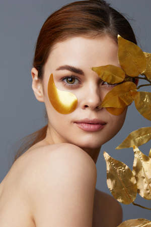 pretty woman golden leaves luxury skin care face patches bare shoulders close-up Lifestyleの写真素材