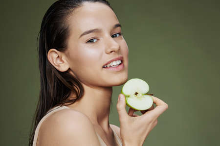 young woman green apple near face health isolated backgroundの写真素材
