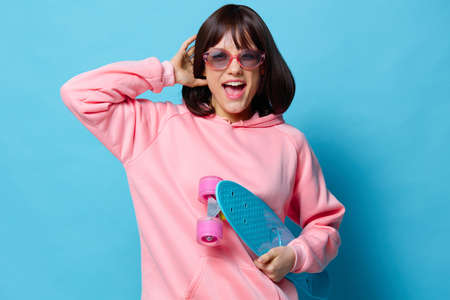 portrait woman in a pink sweater skateboard entertainment isolated backgroundの写真素材