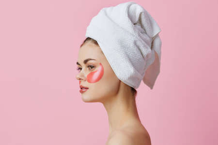 woman pink patches on the face with a towel on the head isolated backgroundの写真素材