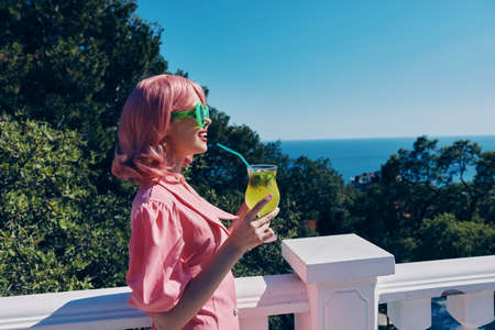Young female enjoying a colorful cocktail hotel terrace Happy female relaxing