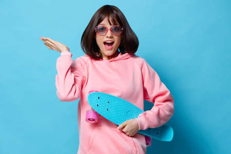 portrait woman teenager skateboard emotions youth style blue backgroundの写真素材