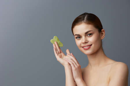 pretty woman scraper gua sha facial care home facial massage Gray backgroundの写真素材