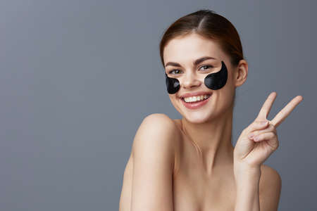 portrait woman eye patches on face bare shoulders skin care isolated backgroundの写真素材