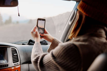 woman in a car takes pictures of nature on the phone. High quality photo