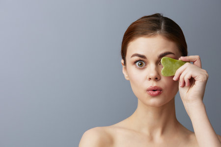 beautiful woman face scraper wrinkle smoothing bare shoulders Gray backgroundの写真素材
