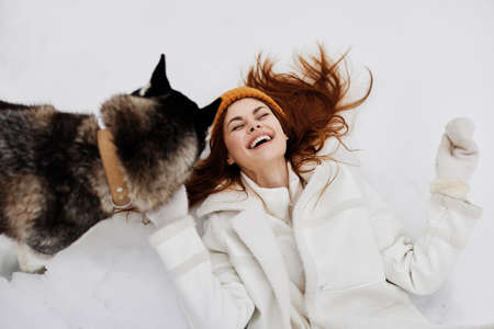 woman in the snow playing with a dog fun friendship winter holidaysの写真素材