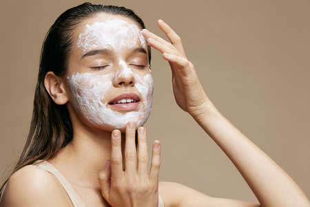brunette cream on cheek posing cosmetics to clean skin close-up make-upの写真素材