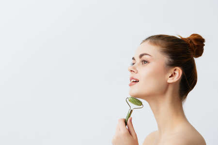 pretty woman jade face massager wrinkle smoothing light backgroundの写真素材