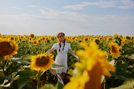 woman with pigtails In a field with blooming sunflowers flowering plants