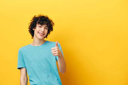 Cheerful guy showing thumb up copy-space yellow backgroundの写真素材