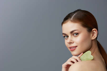 woman scraper gua sha facial care home facial massage isolated backgroundの写真素材