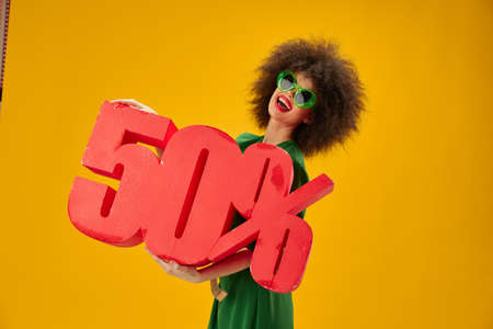 Pretty young female green dress afro hairstyle dark glasses fifty percent in hands studio model unalteredの写真素材