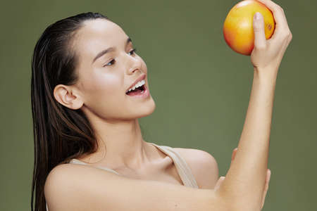 beautiful woman eating grapefruit in hands smile vitamins diet green backgroundの写真素材