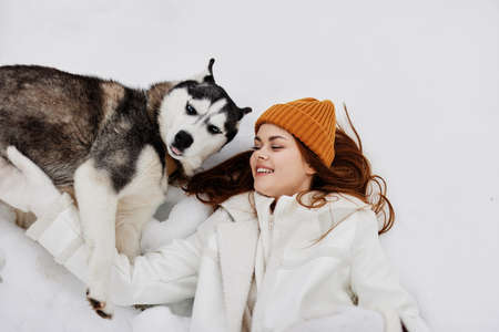 Happy young woman winter clothes walking the dog in the snow fresh air