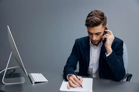 manager business conversation on the phone works in front of a computer Gray background