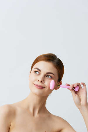 young woman jade face massager wrinkle smoothing smile isolated backgroundの写真素材