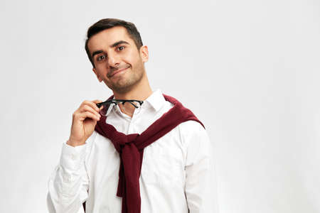 smart businessman in a white shirt sweater on the shoulders pensive look glasses light backgroundの写真素材