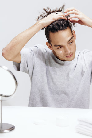 portrait of a man sitting in front of a mirror skin care cosmetics isolated backgroundの写真素材