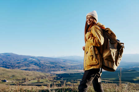 woman in a yellow jacket in a hat backpack travel mountains relaxation