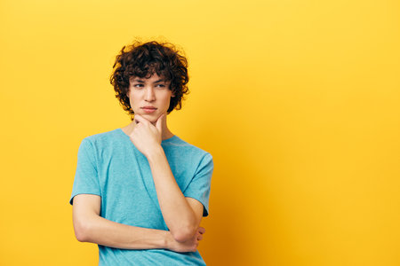 Cheerful teenager in a blue t-shirt on a yellow backgroundの写真素材
