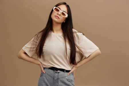 young woman in a beige T-shirt with glasses posing clothing fashion beige background