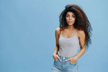COOL JEANS OFFER. Sexy beautiful Latin female with afro hold hands on pocket, look at camera....