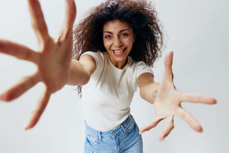 Smiling young afro haired female in casual white basic shirt posing isolated on white background...