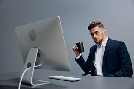 a man in a suit sitting at a desk in front of a computer isolated backgroundの写真素材