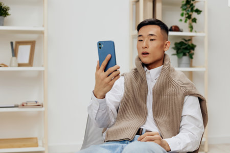 man communication with the phone in his hands sits on a chair interior