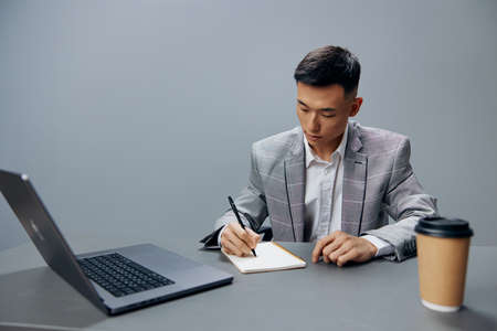 worker sitting at a desk in front of a laptop work writing in a notebook Lifestyle