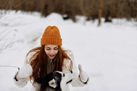 cheerful woman in the snow playing with a dog fun friendship fresh airの写真素材