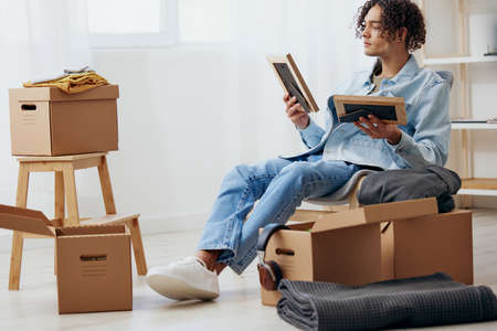 handsome guy unpacking things from boxes in the room sorting things out