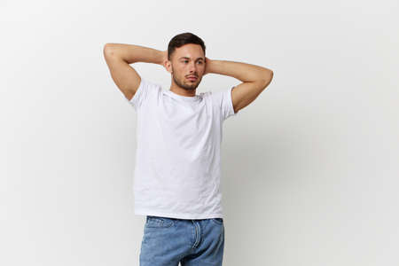 Young sexy happy tanned handsome man in basic t-shirt folded hands behind head posing isolated on over white studio background. Copy space Banner Mockup. People emotions Lifestyle conceptの写真素材