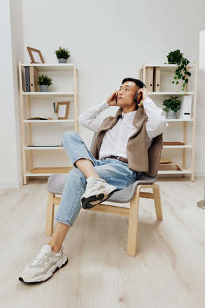 Asian man in headphones sits on a chair rest music Lifestyleの写真素材