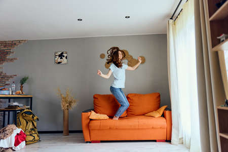 pretty woman in jeans is standing on the couch funの写真素材