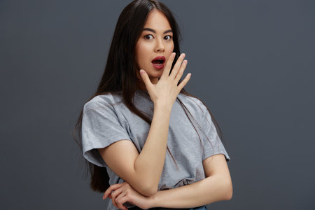 portrait woman with long hair in a gray T-shirt gesturing with hands Gray backgroundの写真素材