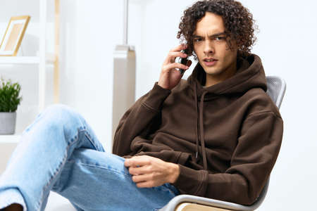 guy with curly hair chatting in the room on the phone technologiesの写真素材