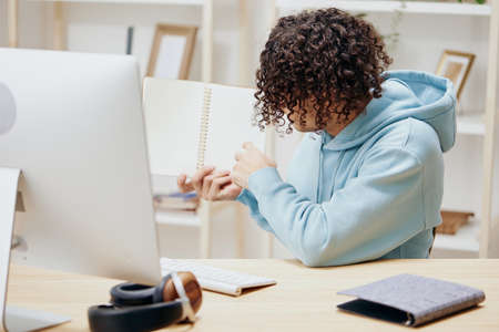guy with curly hair in a blue jacket in front of a computer with phone technologies