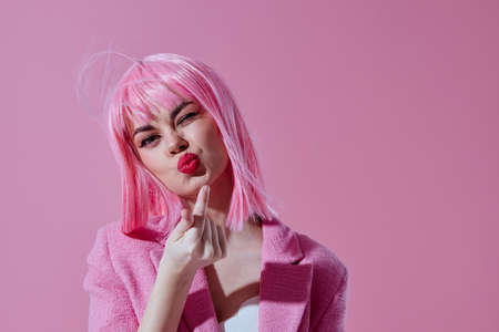 Young woman pink jacket holding hair cosmetics pink background unaltered