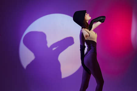 Beautiful fashionable girl posing on stage spotlight silhouette disco purple background unaltered