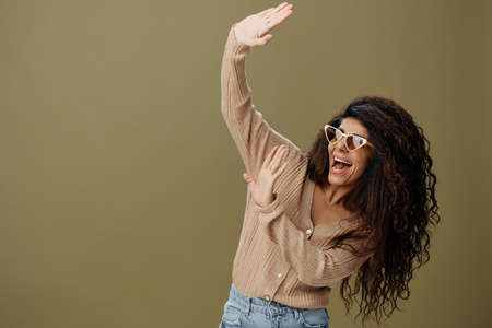 SUNSHINE CONCEPT. Happy enjoyed tanned curly Latin female in casual things sunglasses closed from...