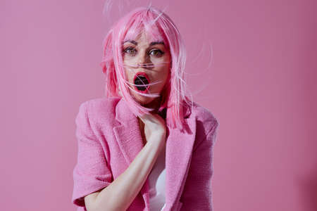 Beautiful fashionable girl in a pink blazer pink wig cropped view pink background unalteredの写真素材