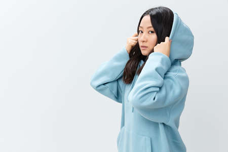 Side of view adorable cute happy Asian young female in blue hoodie sweatshirt posing isolated on...