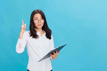 Excited cute Asian businesswoman in classic office dress code holds folder tablet with checklist...