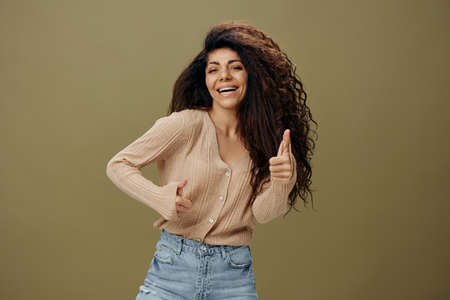 GOOD IDEA CONCEPT. Cheerful smiling tanned curly Latin female in casual things gesture thumbs up...