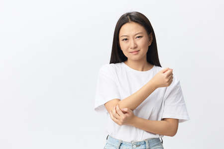 Tormented suffering tanned beautiful young Asian woman hurting holding painful elbow posing isolated...