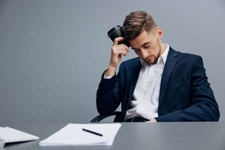 manager drinking coffee tired at work with documents on the table executive