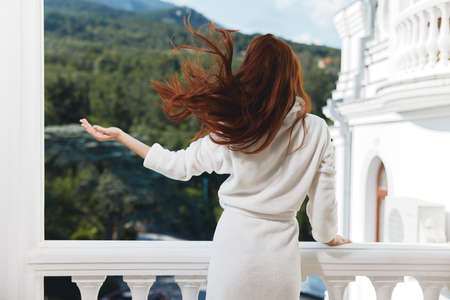 woman in a white robe on the balcony bit on green nature Perfect sunny morningの写真素材